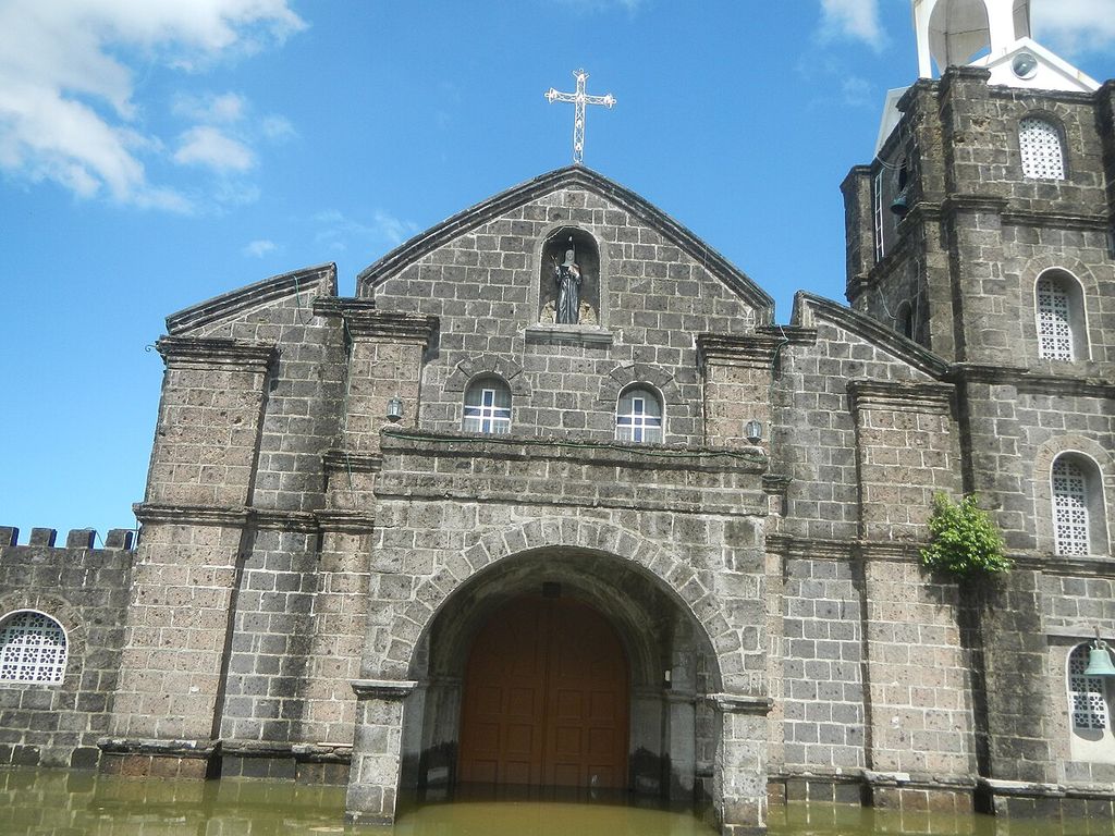 A stone church whose doorway stands in floodwater.