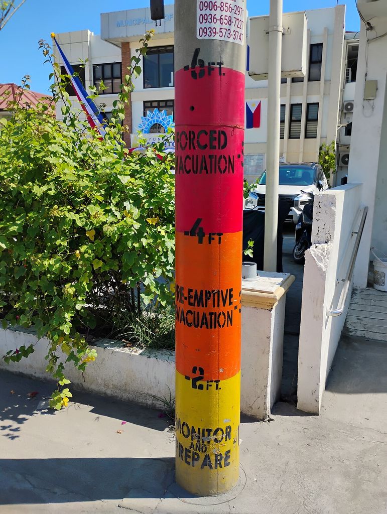 A utility pole painted as a flood gauge: monitor and prepare at 2 feet, pre-emptive evacuation at 4 feet, forced evacuation above.